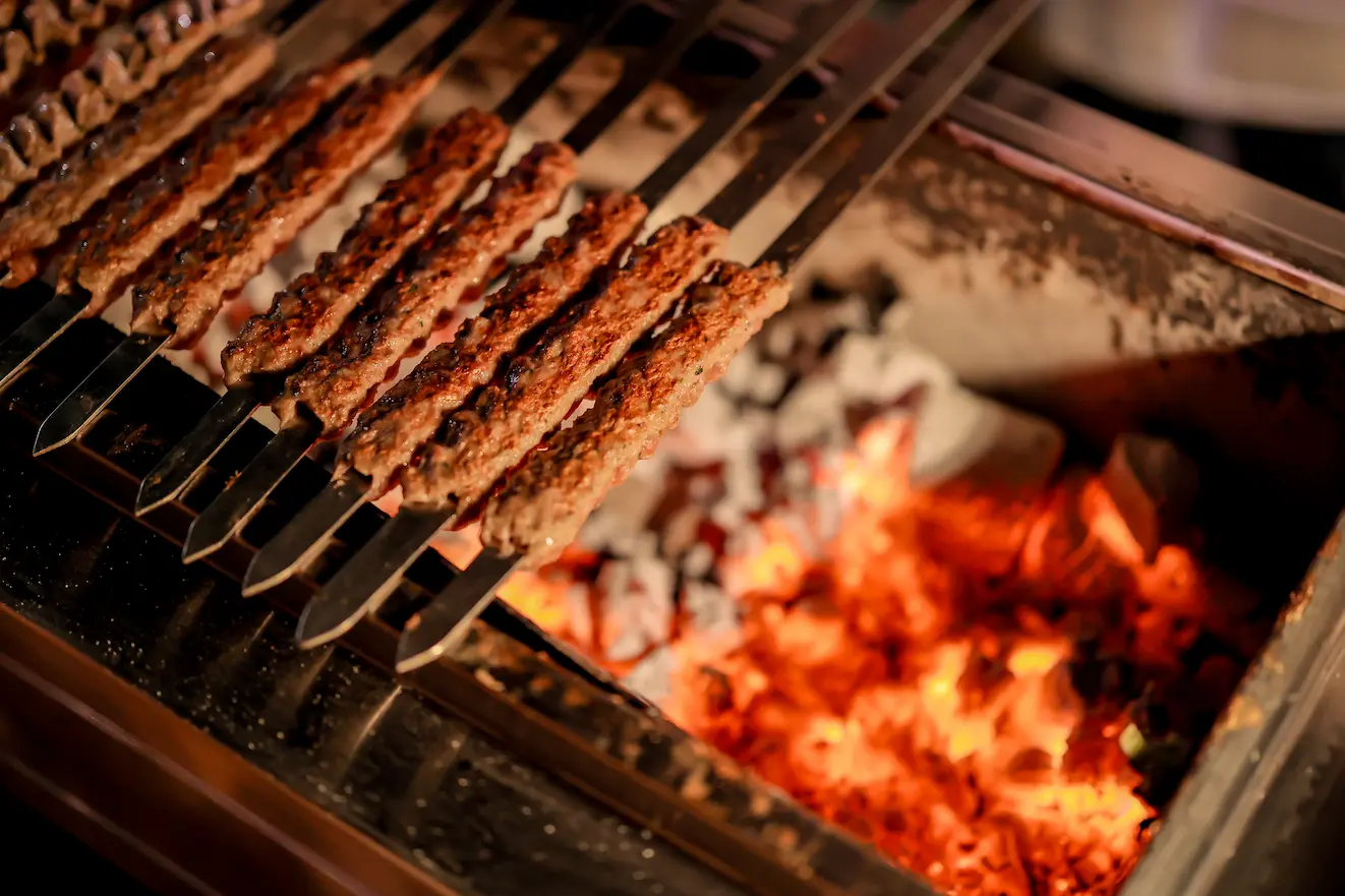 Kebabs grilling over hot charcoal at a luxury desert wedding live cooking station