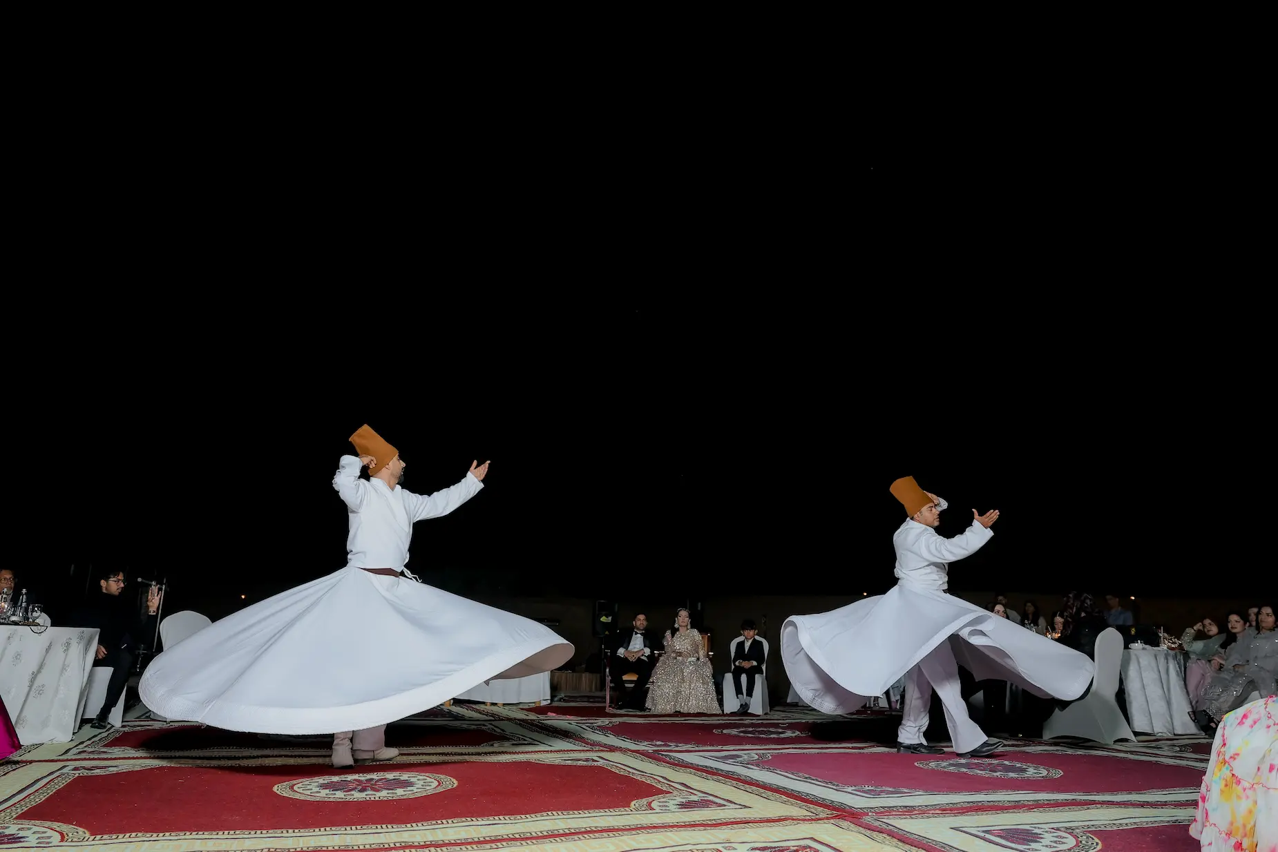 Whirling dervish performers spinning on ornate carpets at a luxury desert wedding celebration