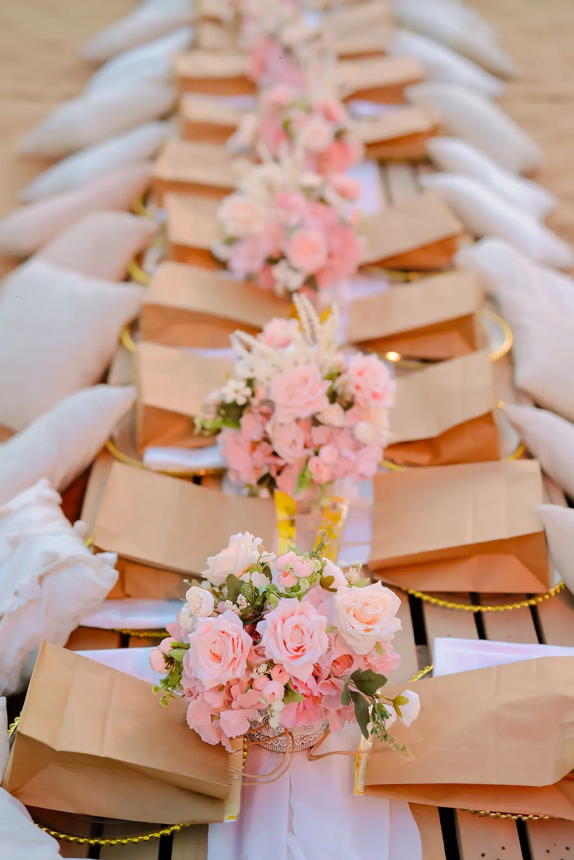 Rows of elegant gift bags with pink rose bouquets at a luxury desert wedding celebration
