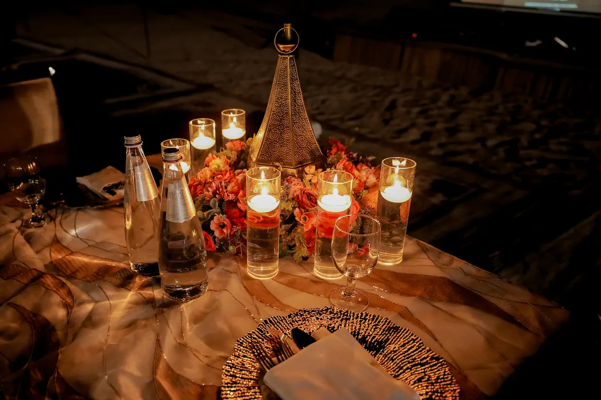 Intimate candlelit table setting with Moroccan lantern and orange florals at desert wedding